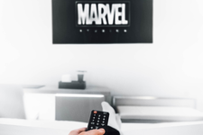 A remote being pointed at a screen with the Marvel logo on it