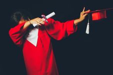Person holding degree certificate and graduation cap while dabbing