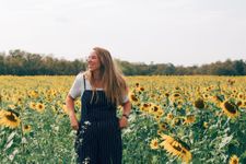 Woman smiling stood in a sunflower field